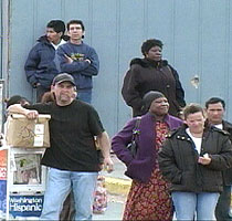 Day laborers wait in the parking lot for potential employers